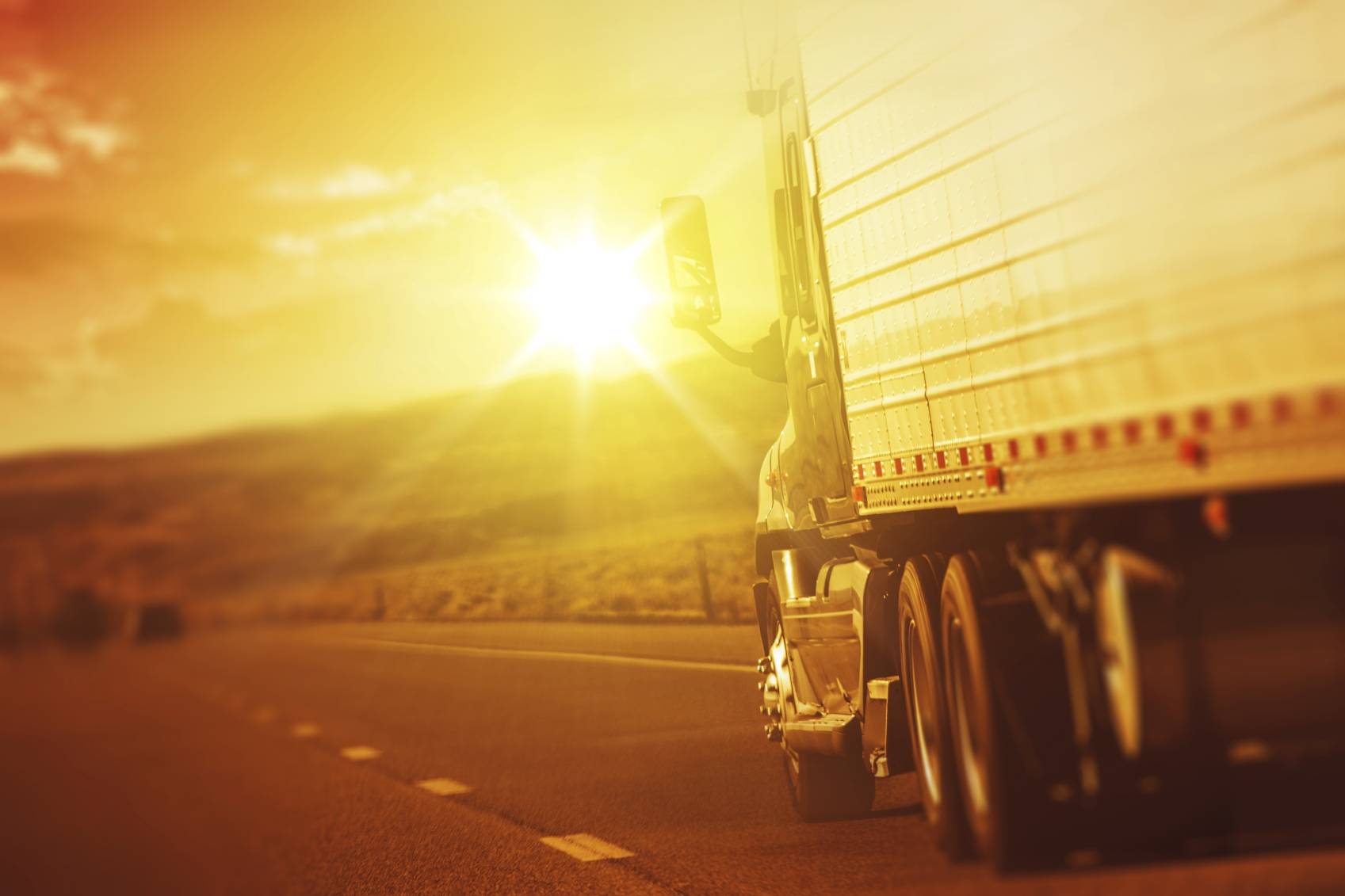 18 wheeler truck driving toward sun