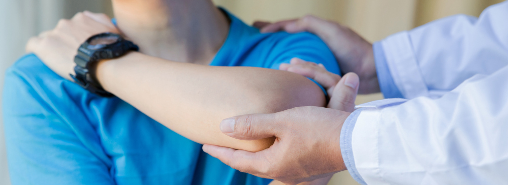 A doctor examining a man's injured shoulder and elbow